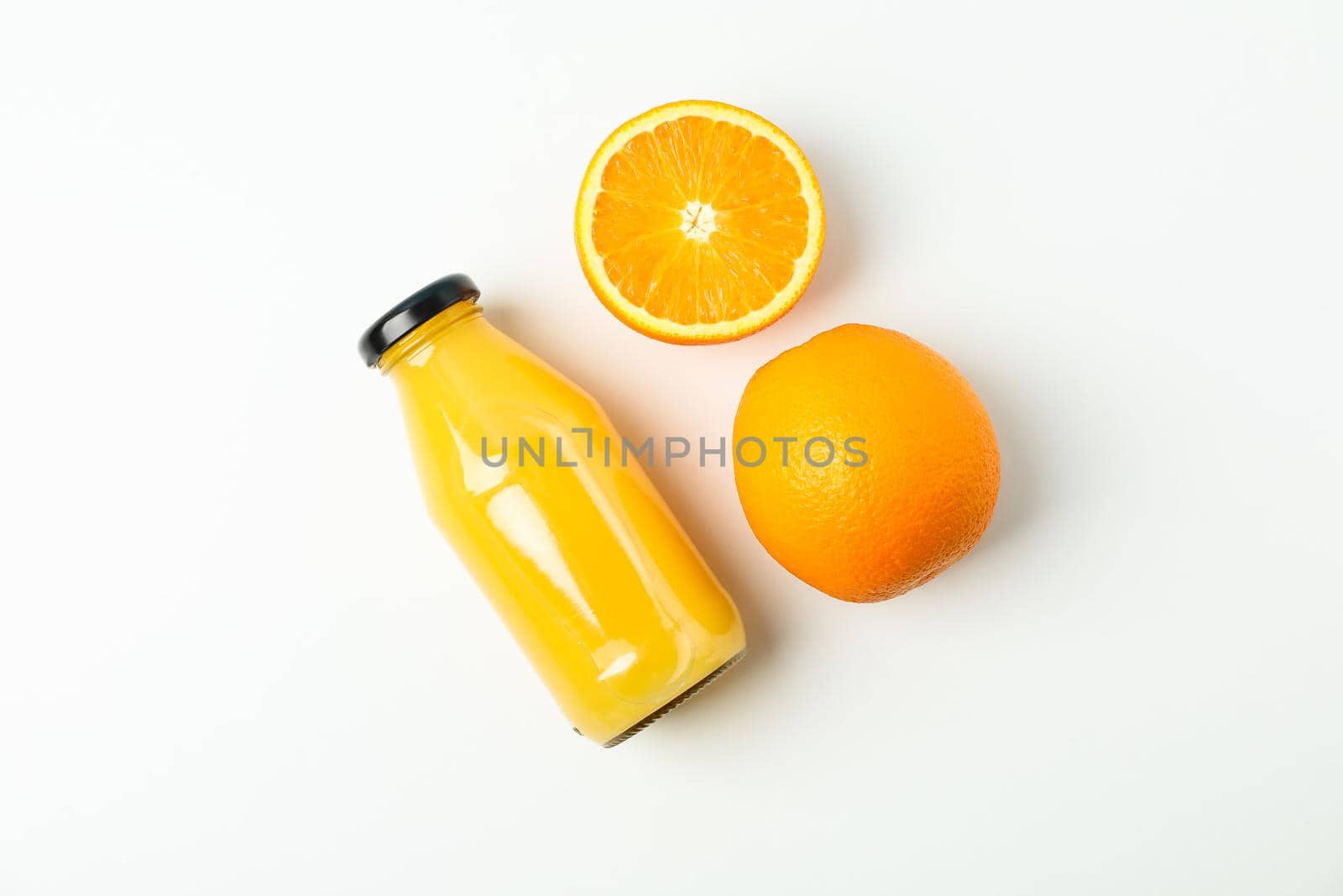 Bottle with fresh natural juice and oranges on white table, space for text. Natural drink by AtlasCompany