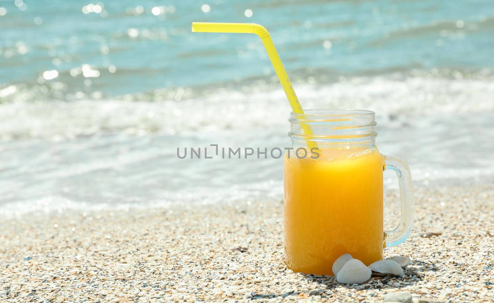 Glass jar of fresh orange juice on seaside, space for text. Summer vacation background by AtlasCompany