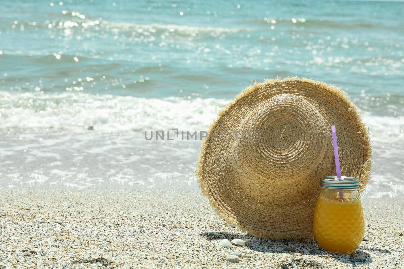 Straw hat and orange juice on seaside, space for text. Summer vacation background by AtlasCompany
