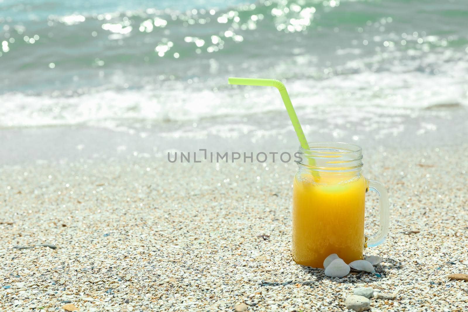 Glass jar of fresh orange juice on seaside, space for text. Summer vacation background by AtlasCompany