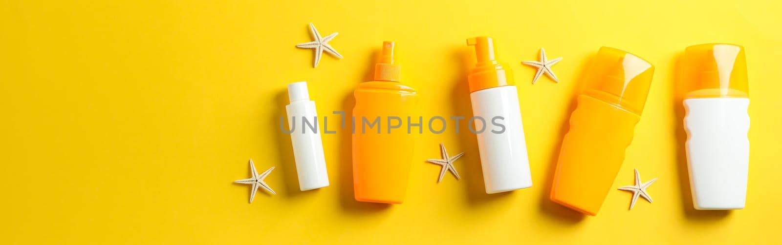 Flat lay composition with sunscreen sprays and starfishes on color background, space for text. Summer vacation backdrop by AtlasCompany