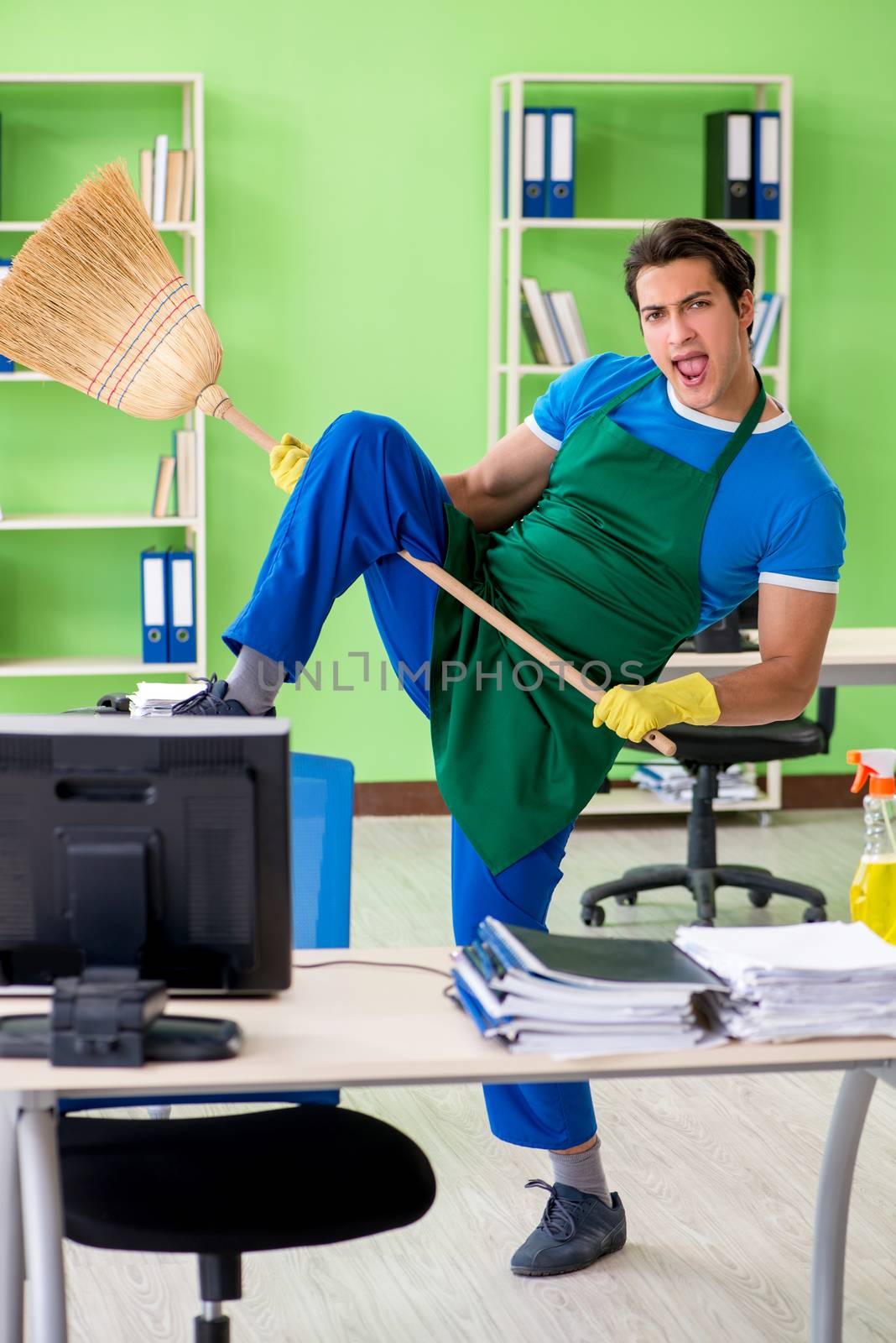 Young male handsome professional cleaner cleaning floor with broom