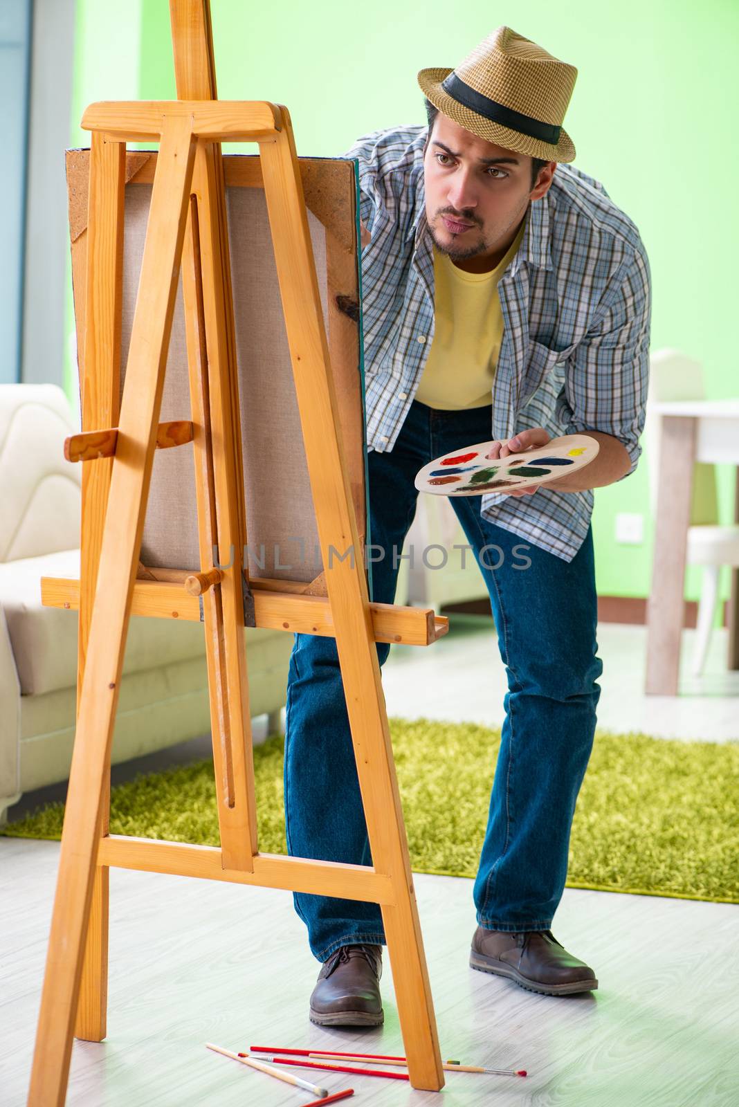 Young male artist working on new painting in his studio