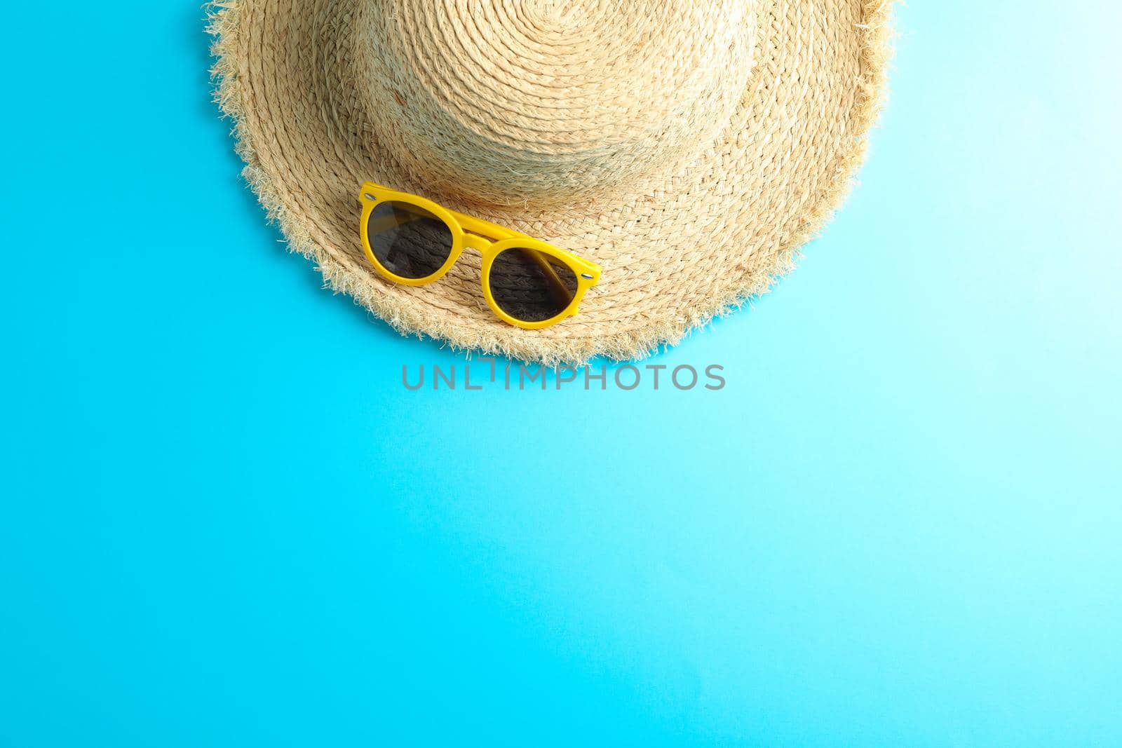 Straw hat and sunglasses on color background, space for text by AtlasCompany