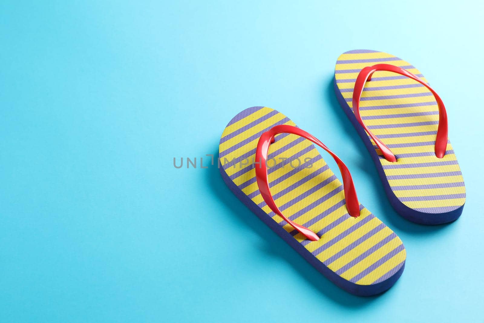 Flip flops on color background, space for text. Summer vacation backdrop by AtlasCompany
