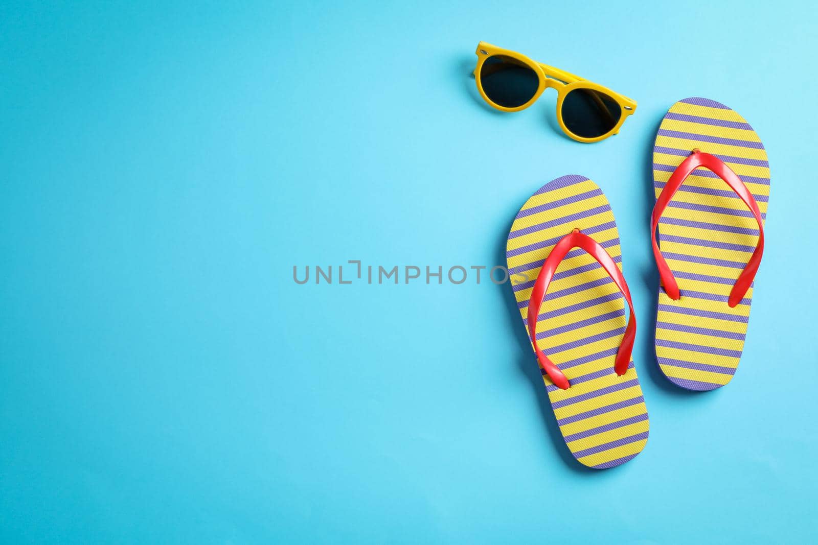 Sunglasses and flip flops on color background, space for text by AtlasCompany