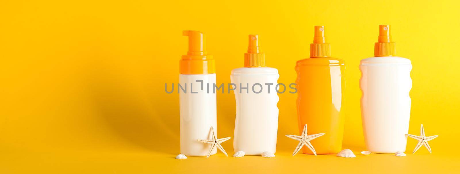 Sunscreen sprays with starfishes on color background, space for text. Safe tan accessories