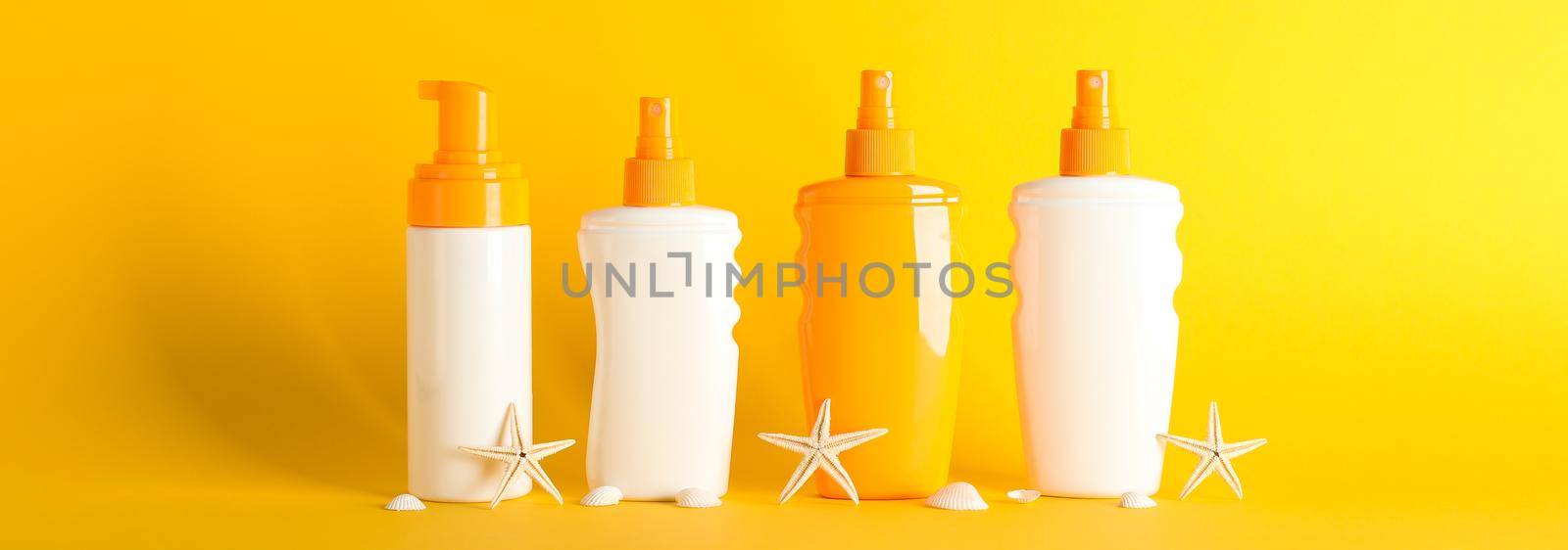 Sunscreen sprays with starfishes on color background, space for text. Safe tan accessories