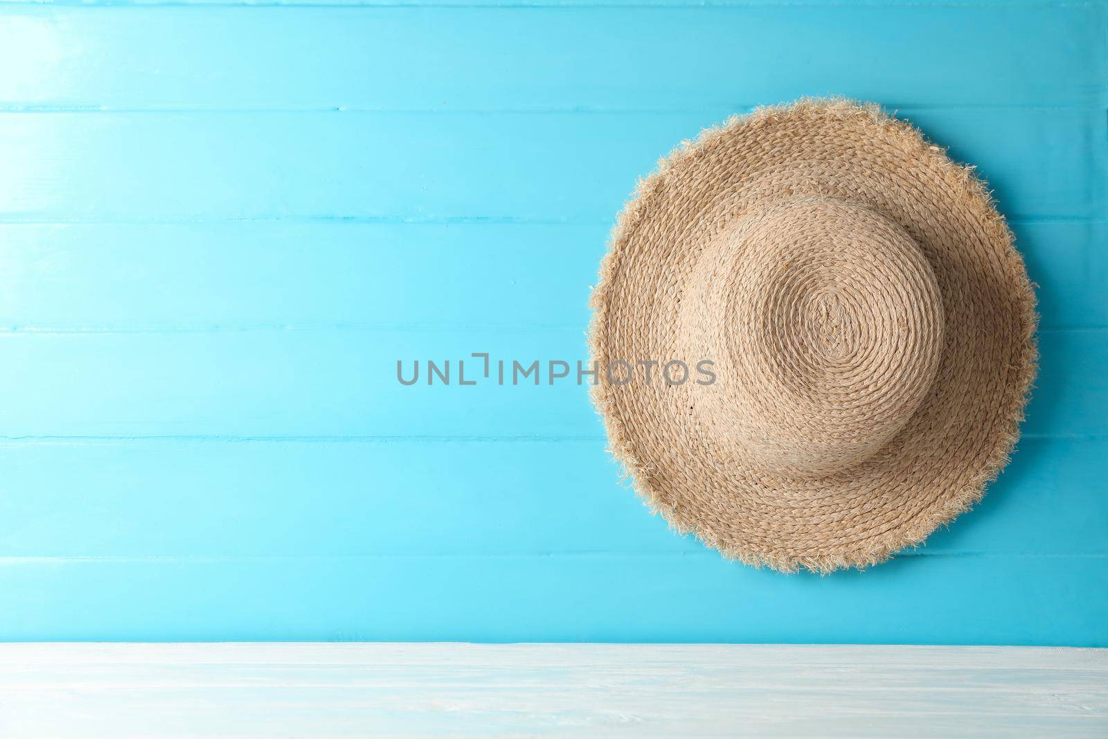 Straw hat on white table against color background, space for text. Summer vacation backdrop