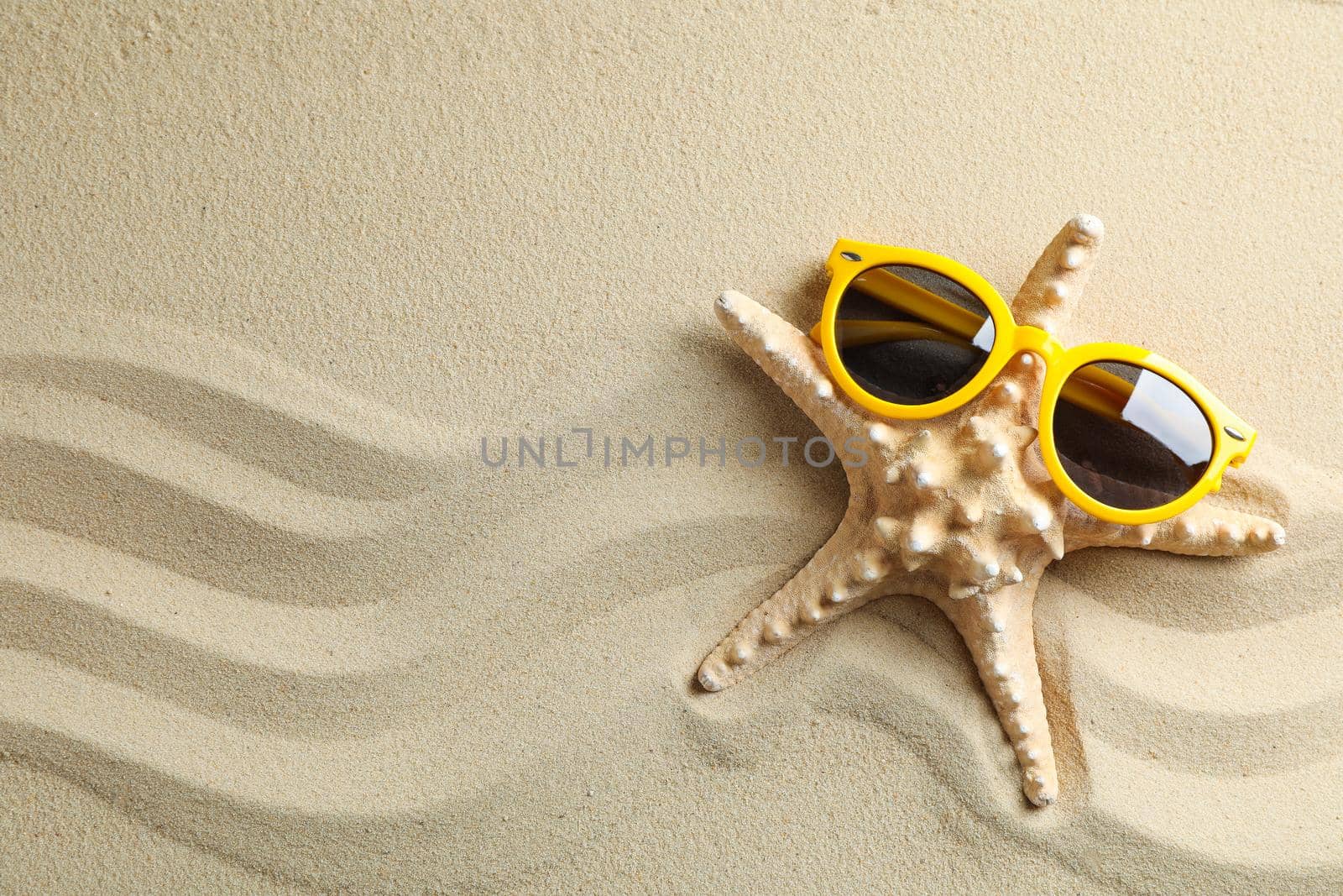 Clear sea sand with starfish and sunglasses, space for text. Summer vacation background