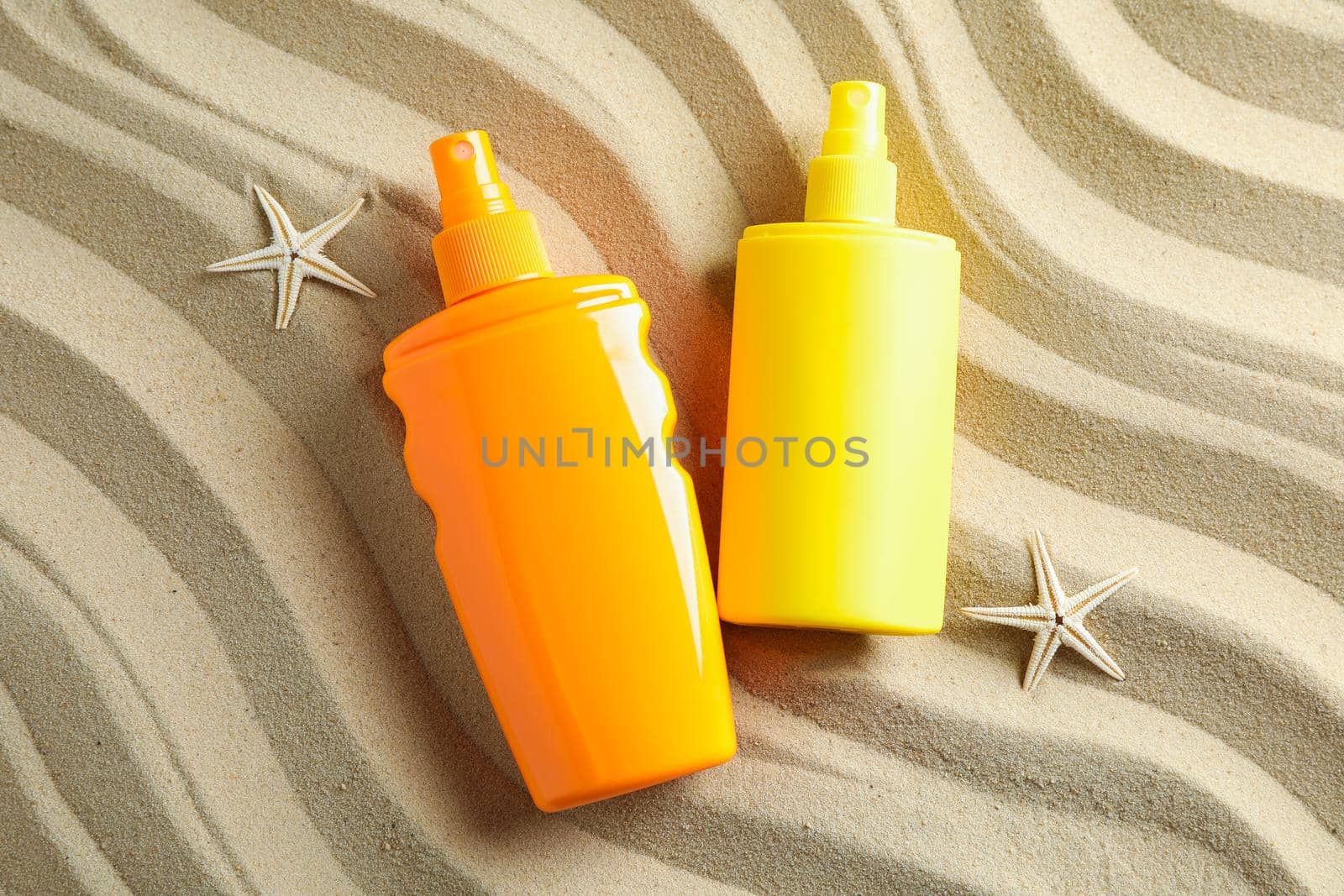 Clear sea sand with starfish and sunscreens, space for text. Summer vacation background