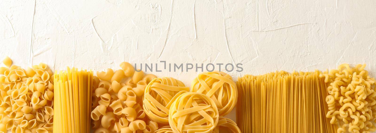 Different pasta on white background, space for text. Dry uncooked whole pasta