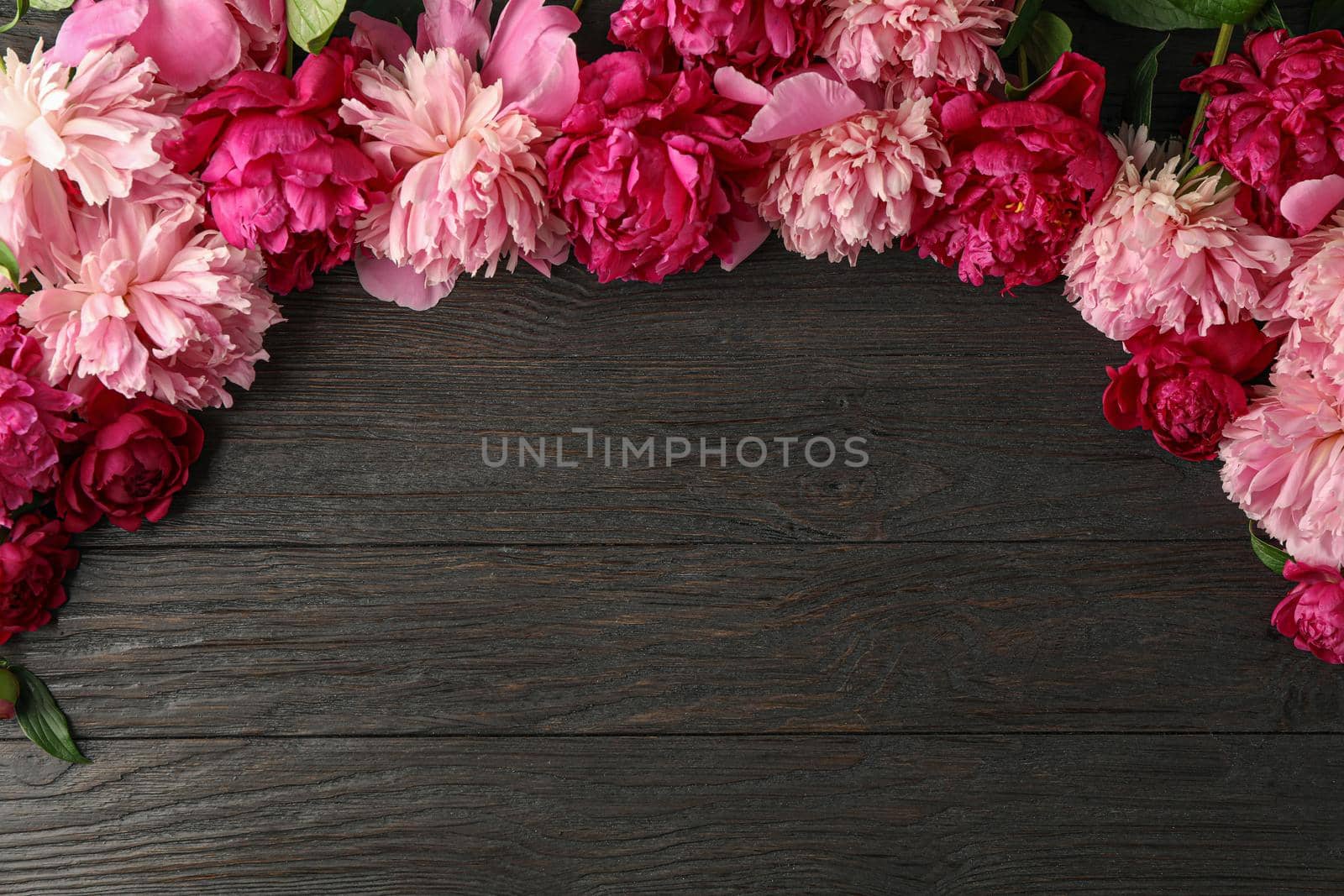 Flat lay composition with beautiful peonies on wooden background, space for text