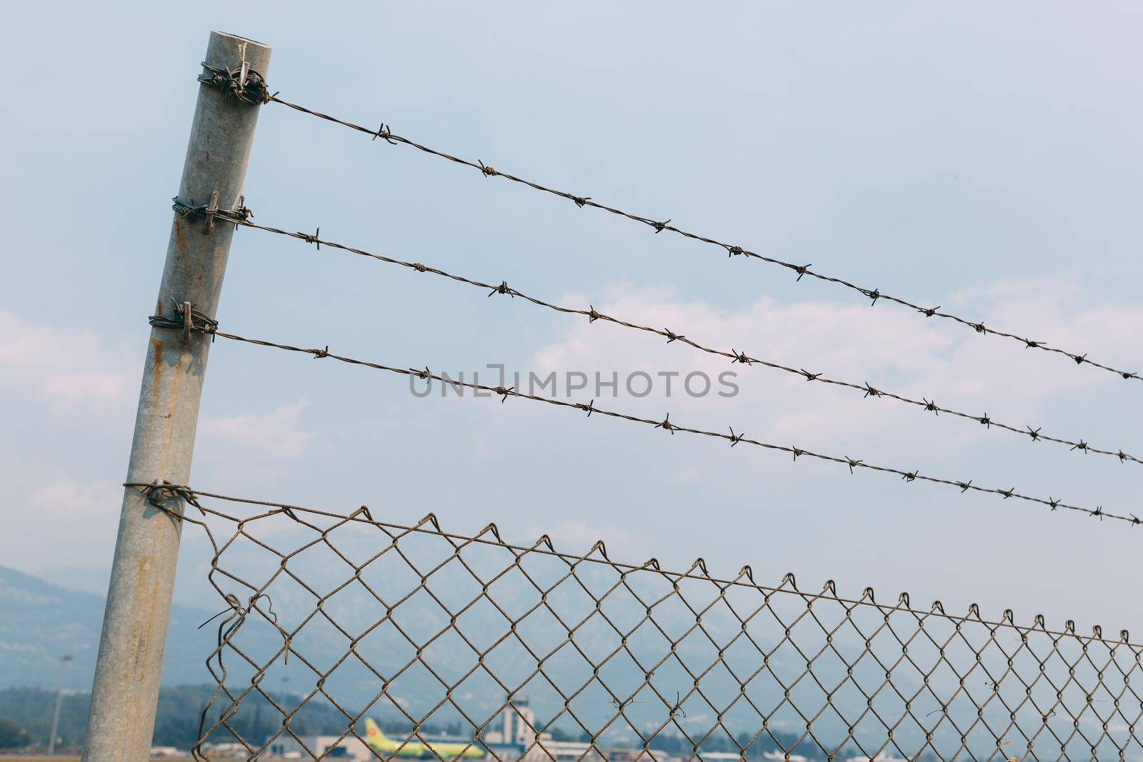 Barbed wire fence against the sky, a fence with a mesh slave at Tivat airport, in Montenegro