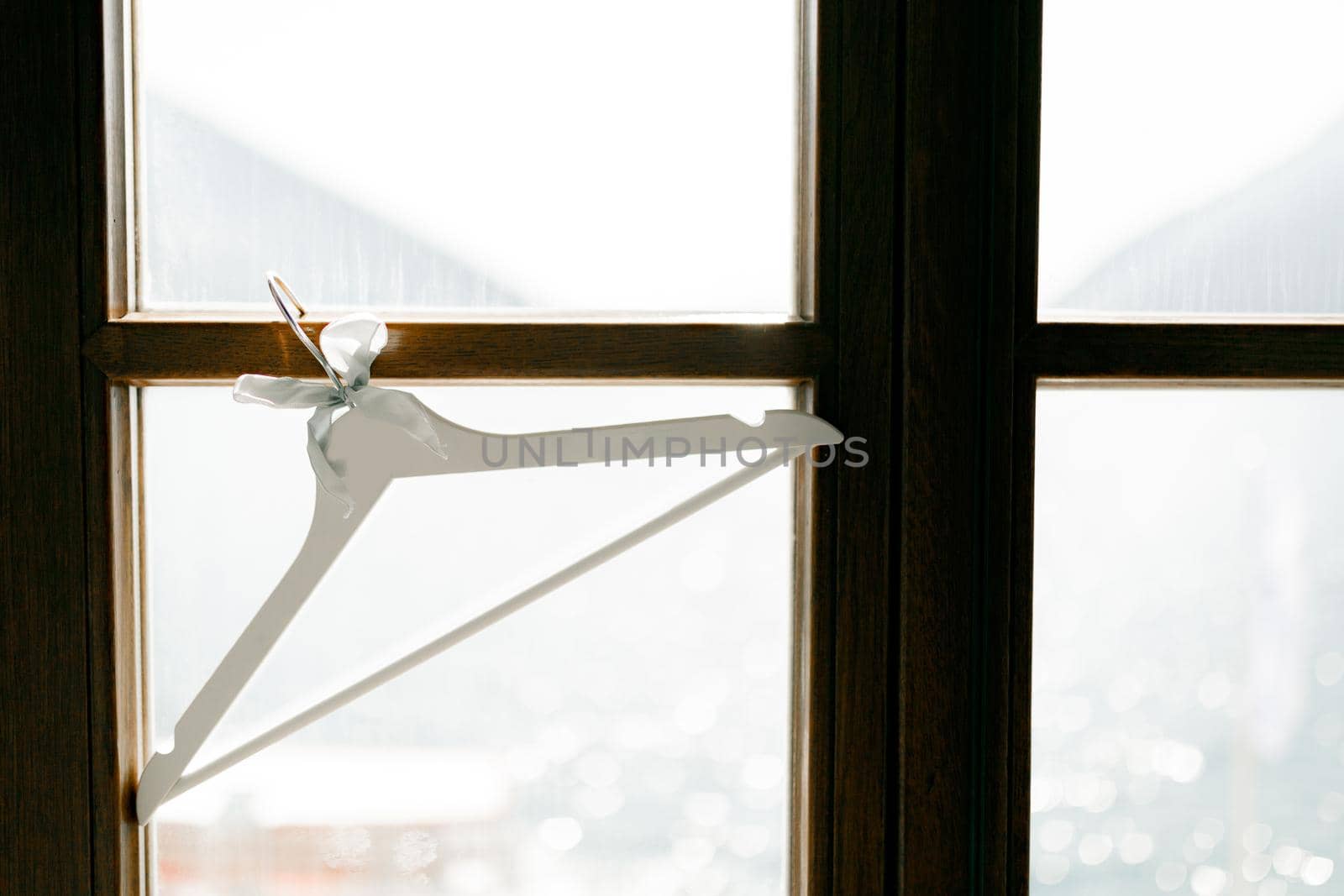 A white clothing hanger hangs on a window against the side of seawater