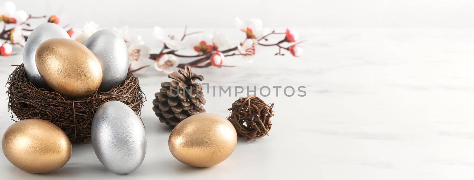 Close up of golden and silver Easter eggs in the nest with white plum flower. by ROMIXIMAGE