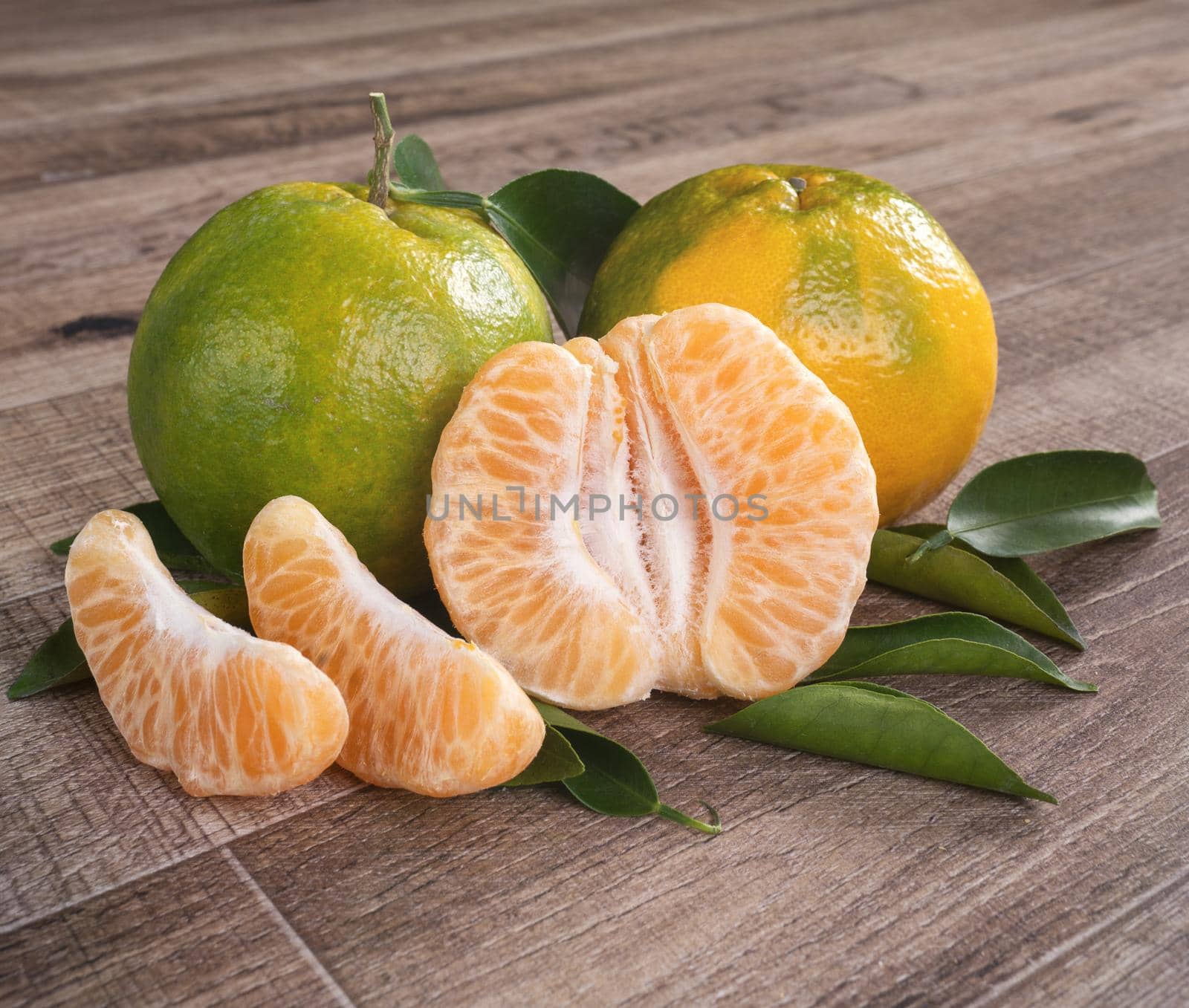 Fresh green tangerine mandarin orange with fresh leaves on dark wooden table background harvest concept.