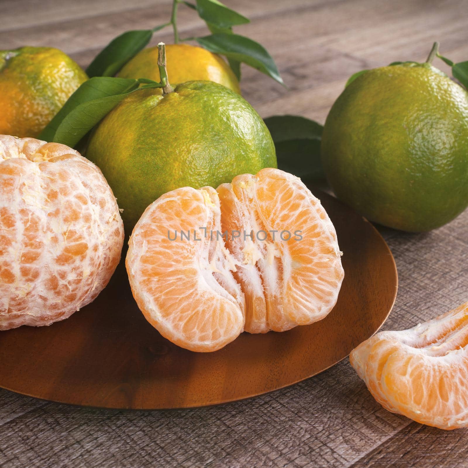 Fresh green tangerine mandarin orange with fresh leaves on dark wooden table background harvest concept.