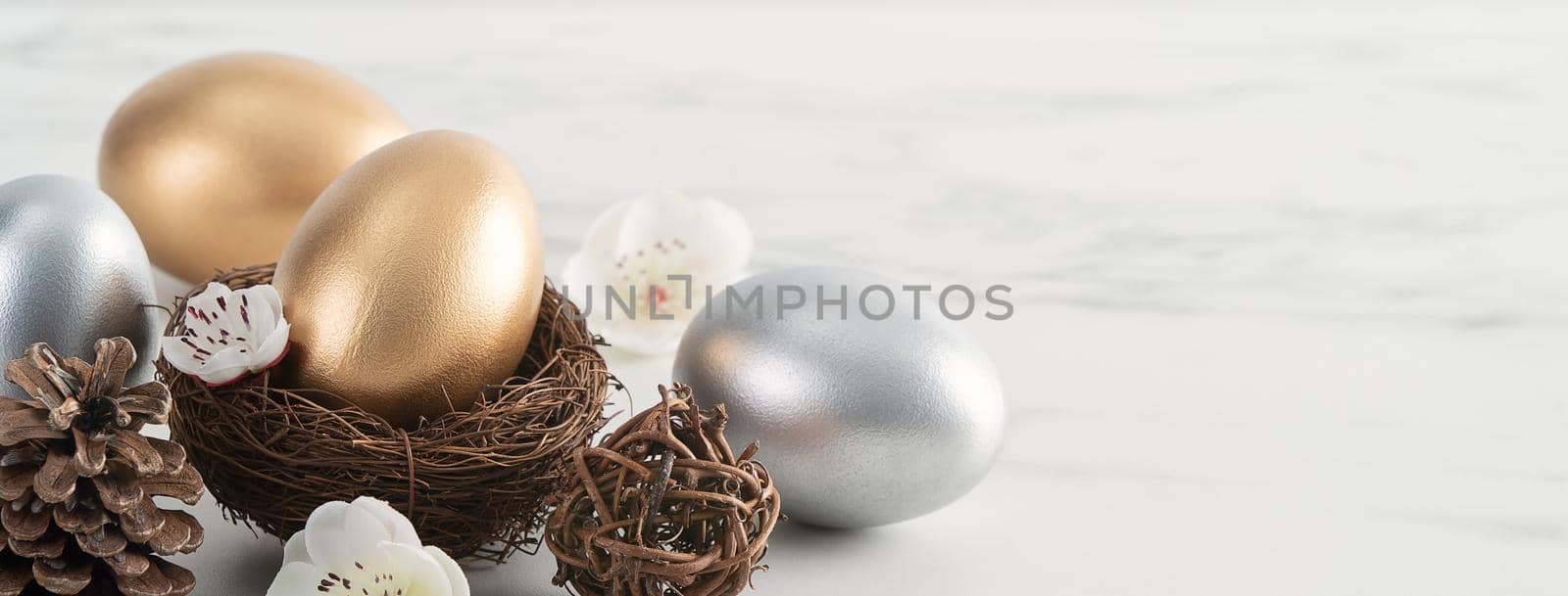 Close up of golden and silver Easter eggs in the nest with white plum flower. by ROMIXIMAGE