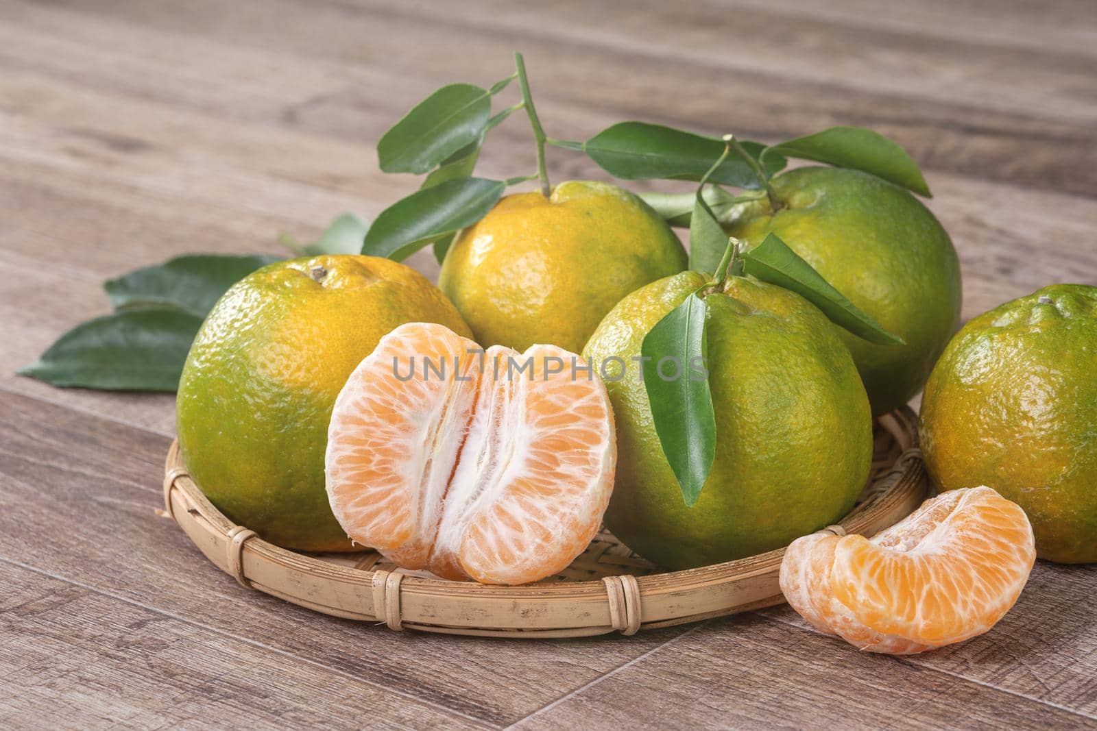 Fresh green tangerine mandarin orange with fresh leaves on dark wooden table background harvest concept.