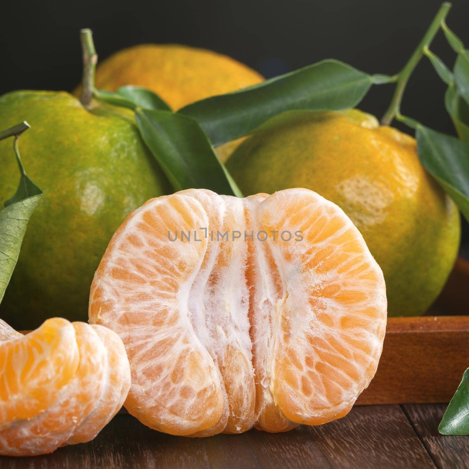 Fresh green tangerine mandarin orange with fresh leaves on dark wooden table background harvest concept.