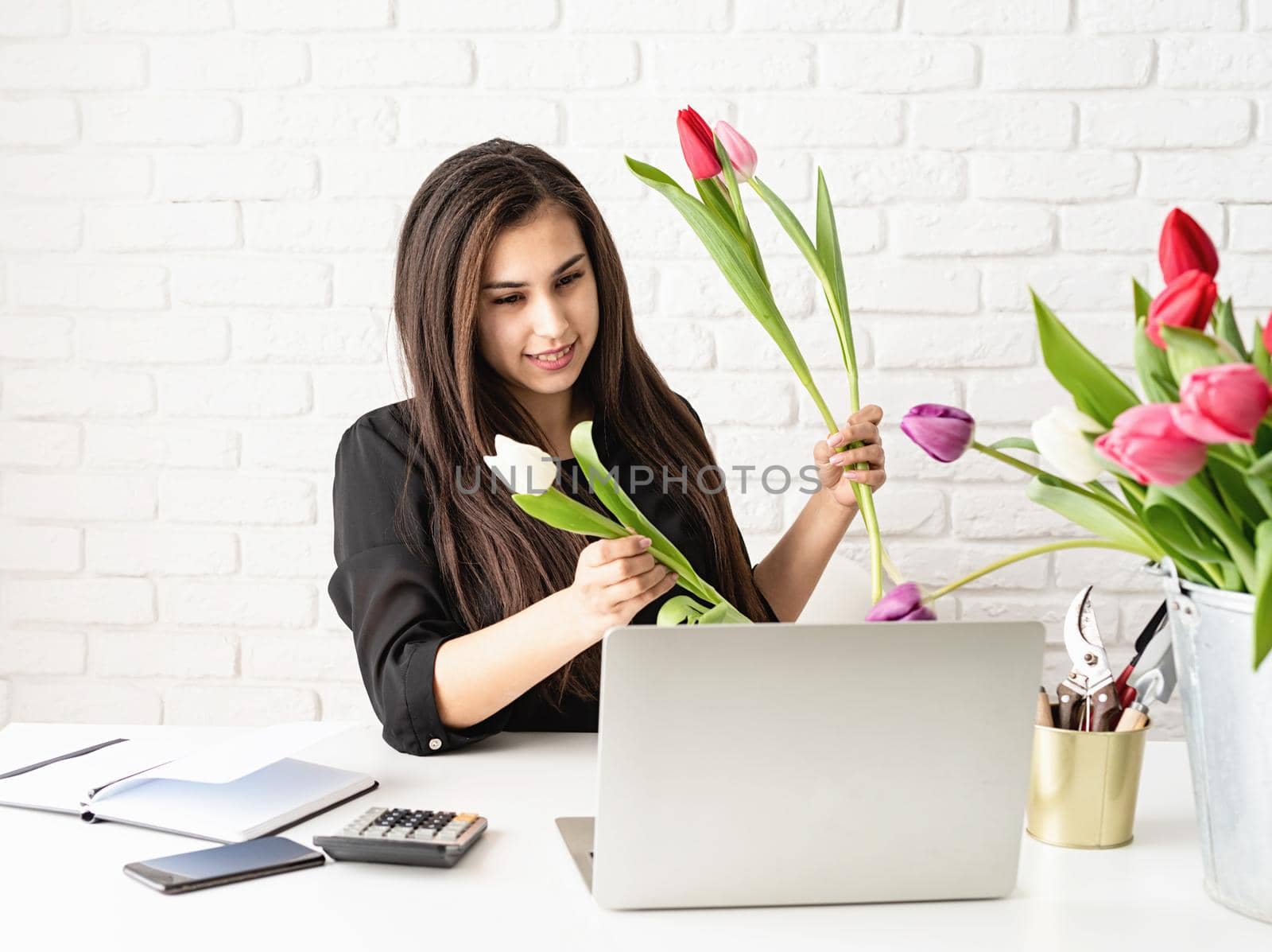A young florist woman working with the client online, selecting flowers for the bouquet by Desperada