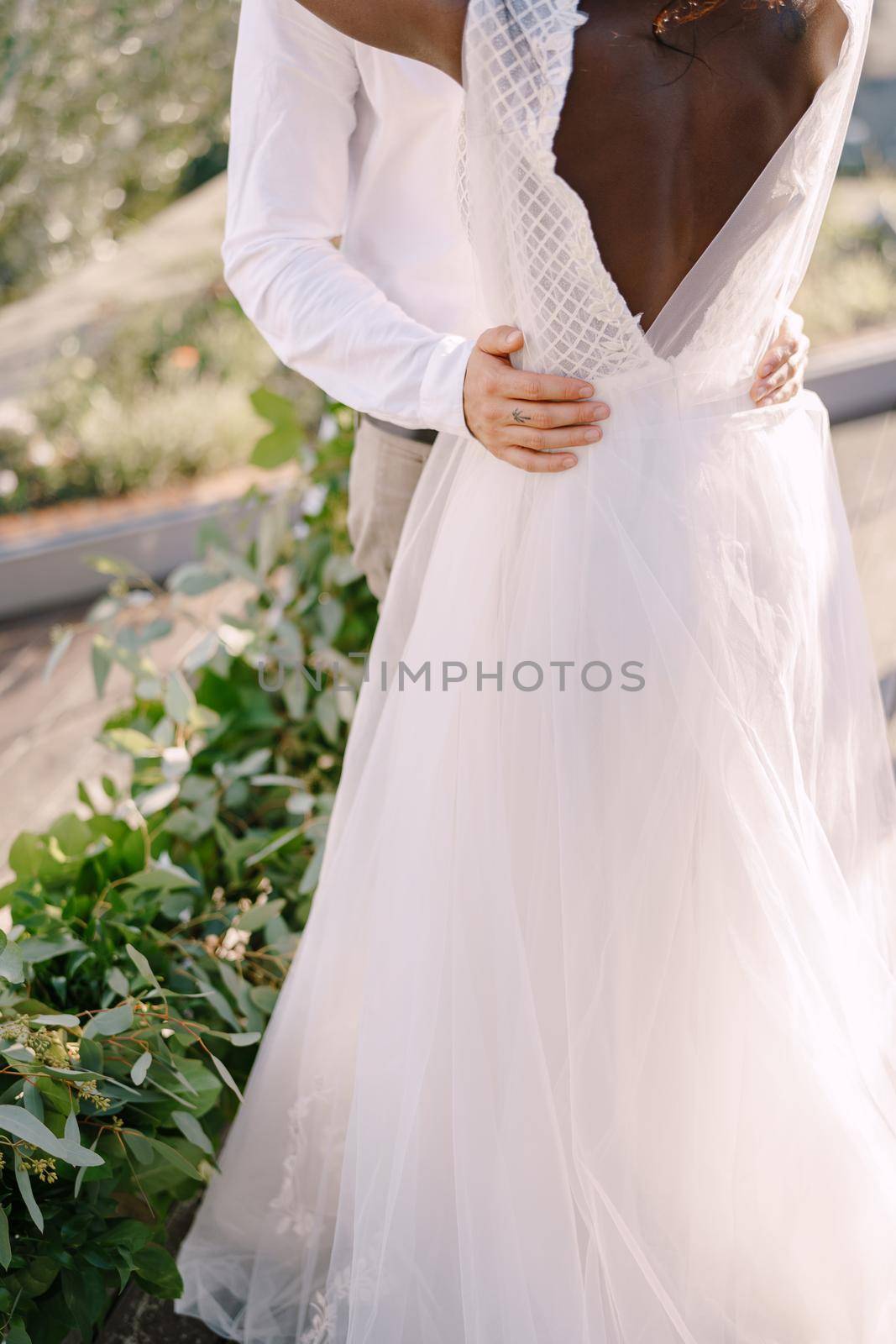 Destination fine-art wedding in Florence, Italy. Interracial wedding couple - African-American bride and Caucasian groom. Groom hugs the bride by the waist.