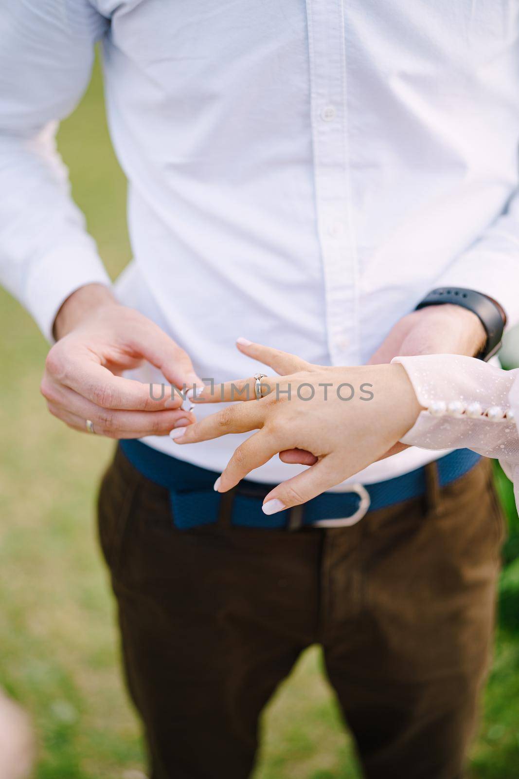 Wedding at an old winery villa in Tuscany, Italy. The groom puts the wedding ring on the brides finger, close-up of hands.