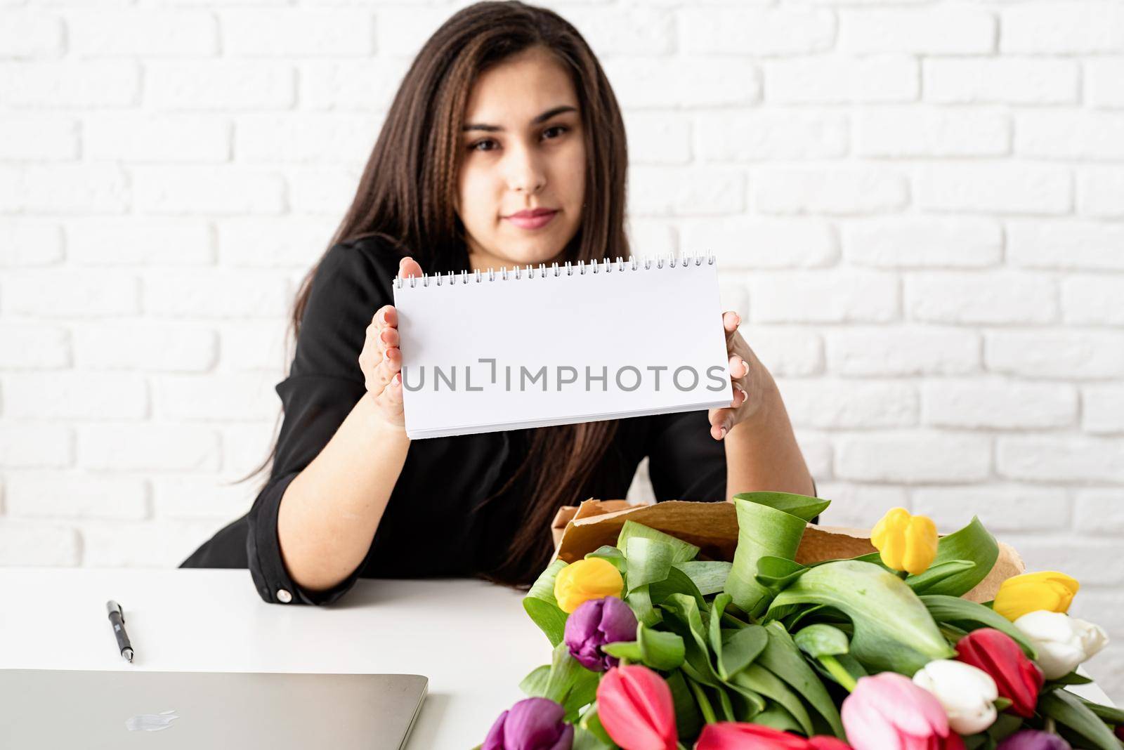 Business woman holding blank desk calendar, working with flowers at the office by Desperada