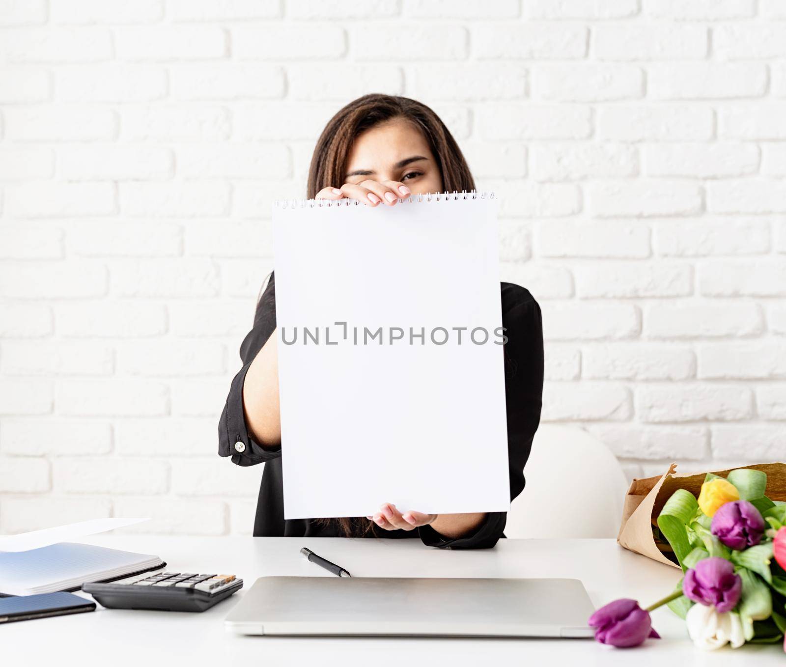 Business woman holding blank wall calendar, working with flowers at the office by Desperada