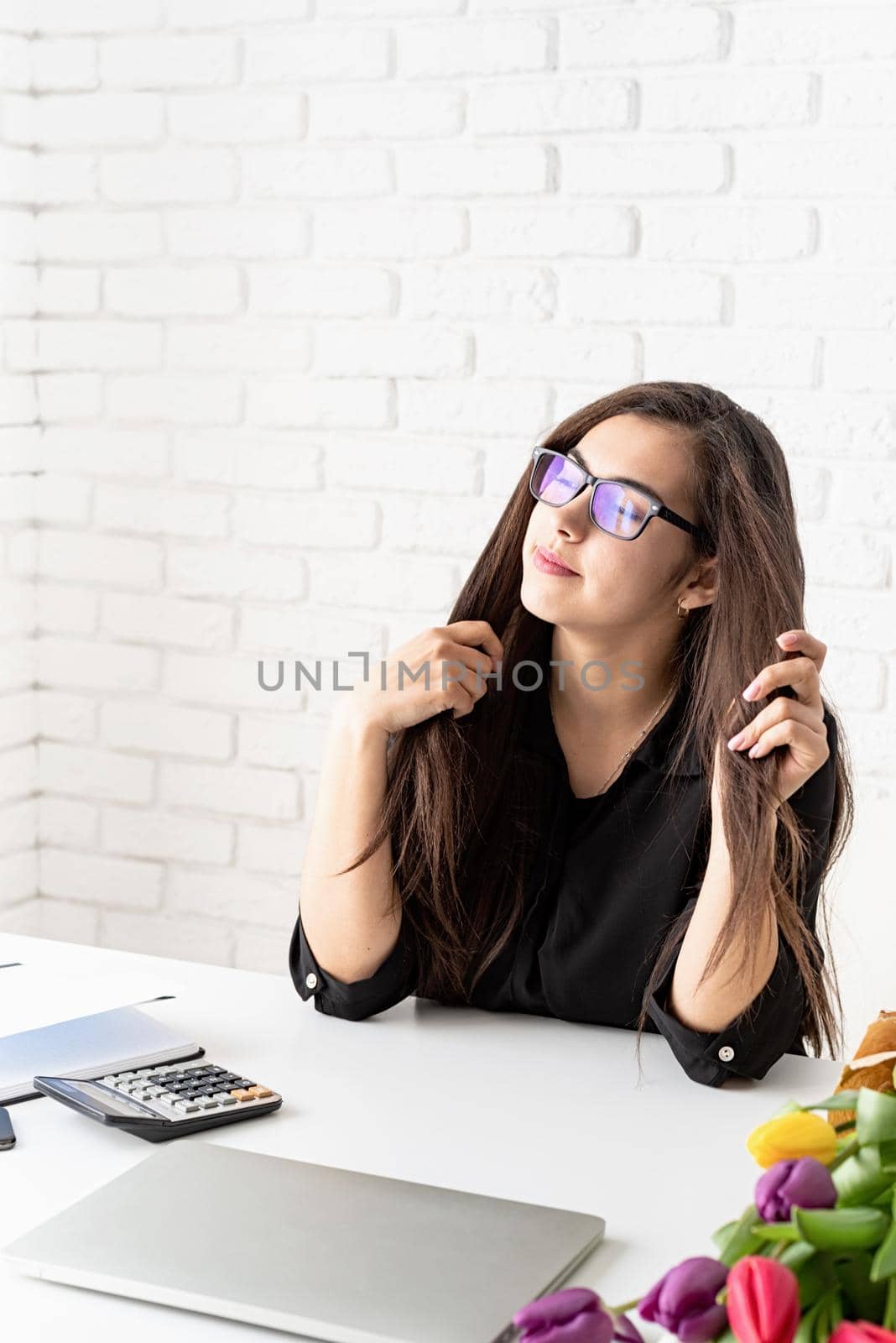 Portrait of young brunette business woman working with flowers at the office by Desperada
