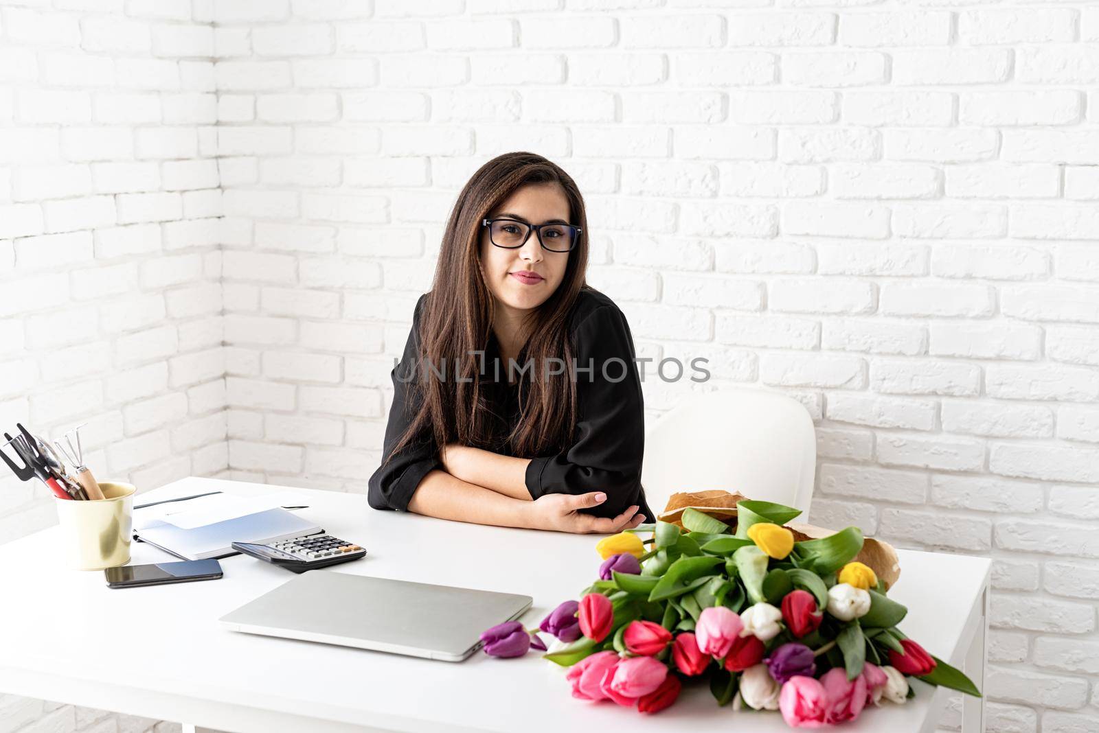 Small business concept. Portrait of young confident business woman working with flowers at the office