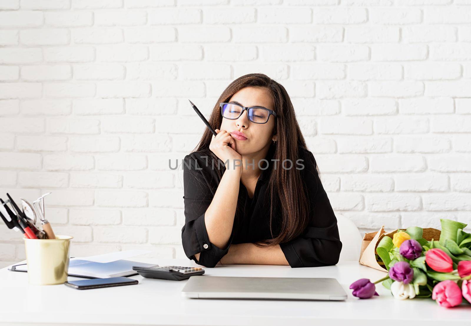 Portrait of young confident brunette business woman working with flowers at the office, thinking with closed eyes by Desperada