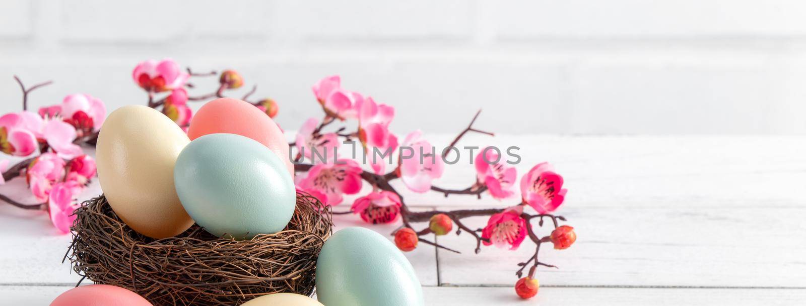 Close up of colorful Easter eggs in the nest with pink plum flower. by ROMIXIMAGE