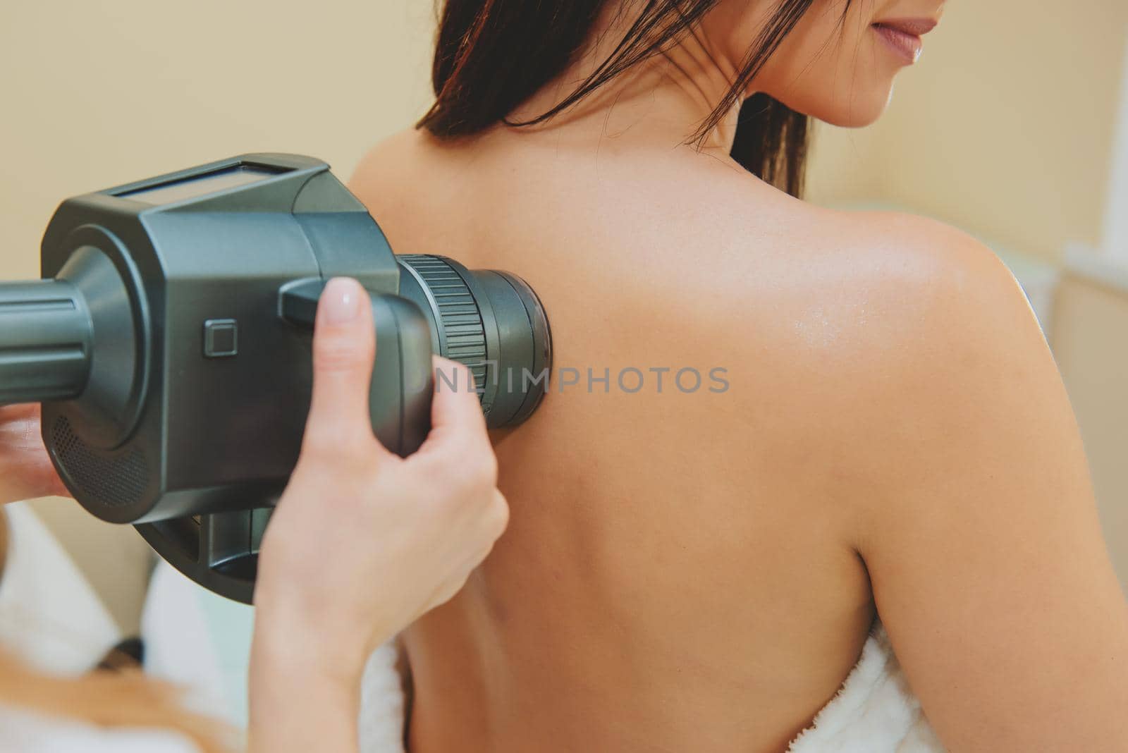 Cosmetologist doing massage with apparatus on female back, close up.