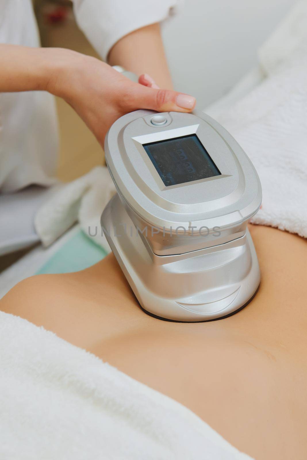 Close-up of cosmetologist doing massage with special apparatus on female belly.