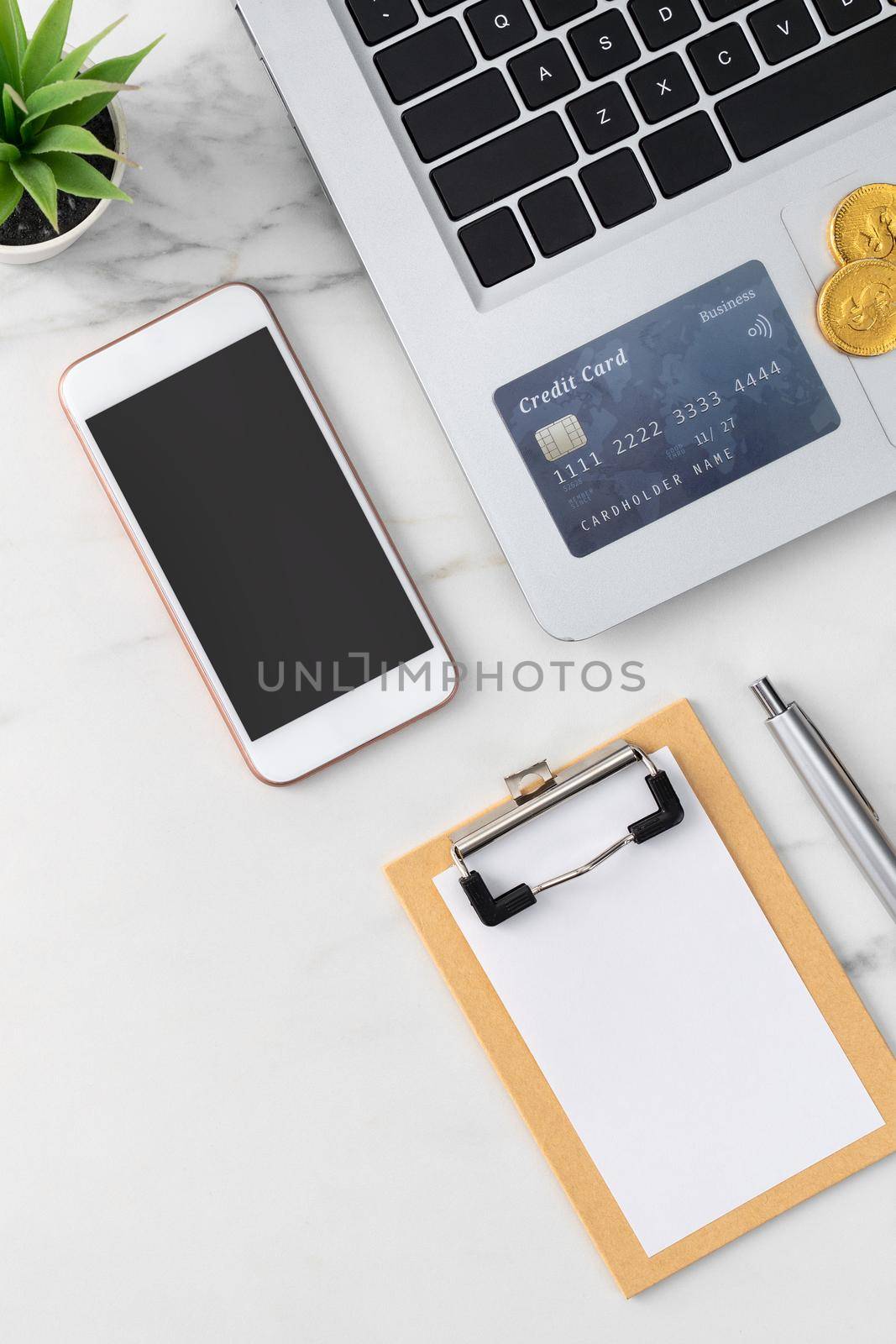 Top view of financial plan concept with credit card, laptop, note on white office table background.