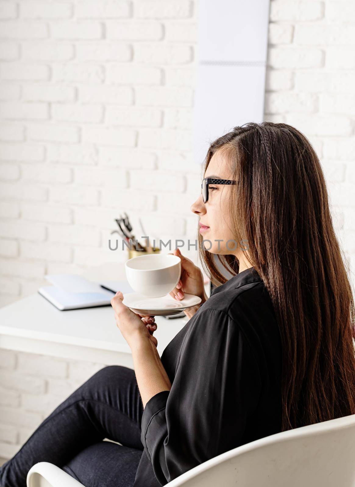 Portrait of young confident brunette business woman working at the office drinking tea or coffee by Desperada