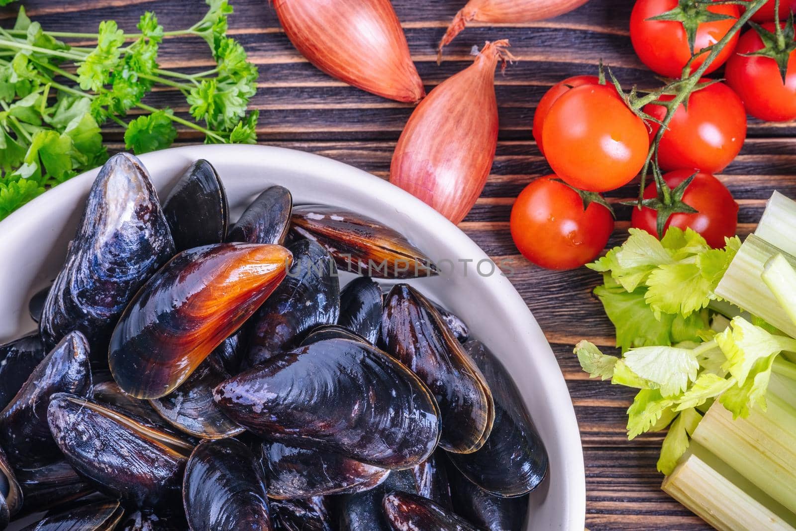 Mussels with parsley in a bowl on a wooden board. Seafood. Dark background