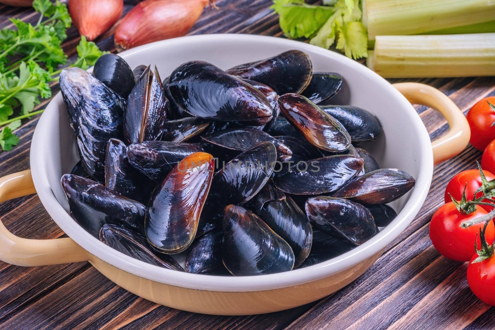 Mussels with parsley in a bowl on a wooden board. Seafood. Dark background