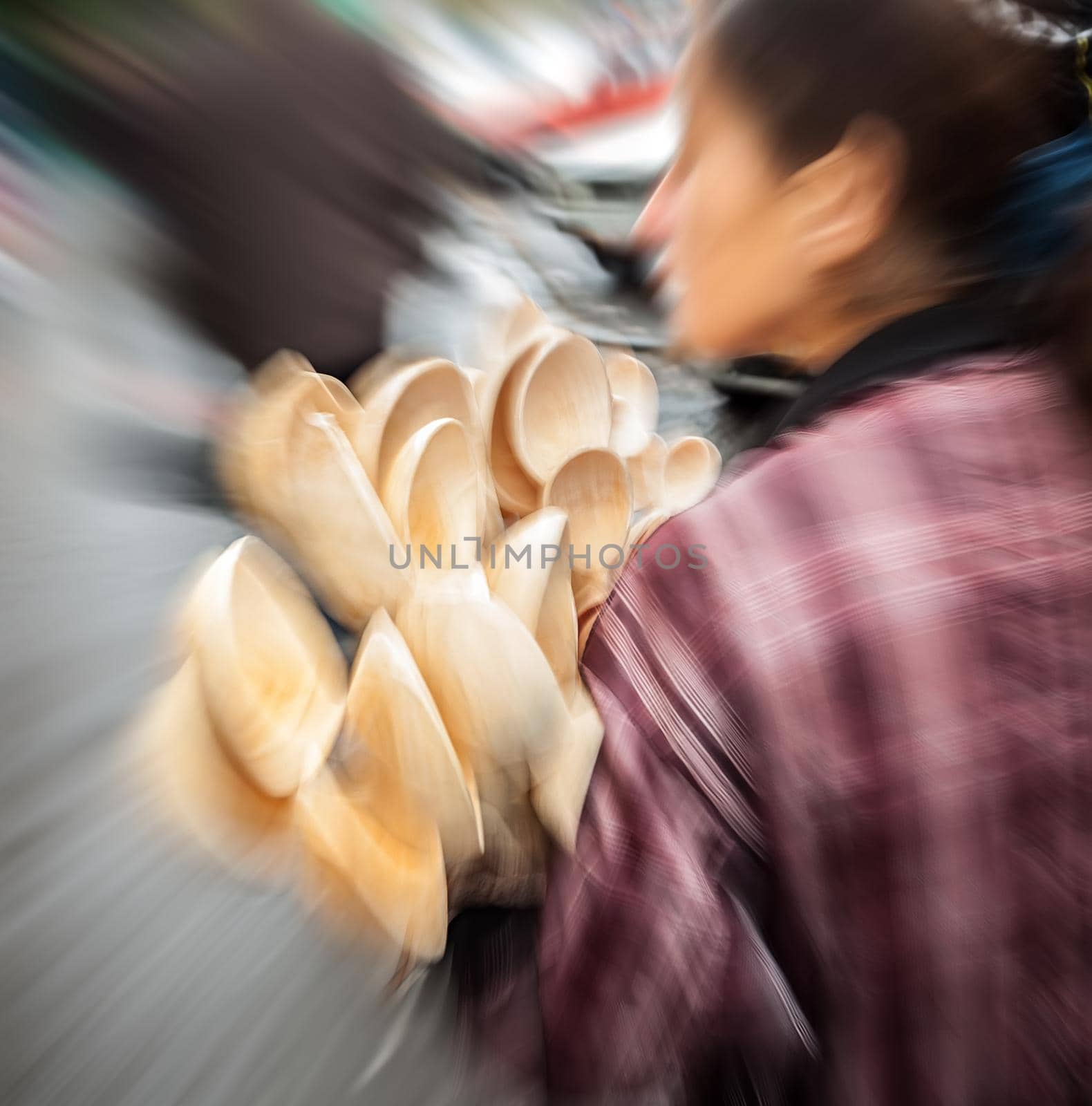 Young woman holding a lot of wooden spoons for sale. Intentional motion blur