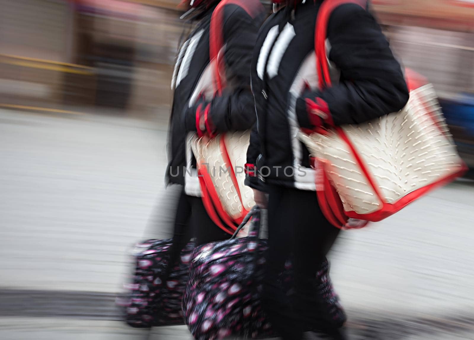 Two young woman at rush hour walking in the street. Intentional motion blur