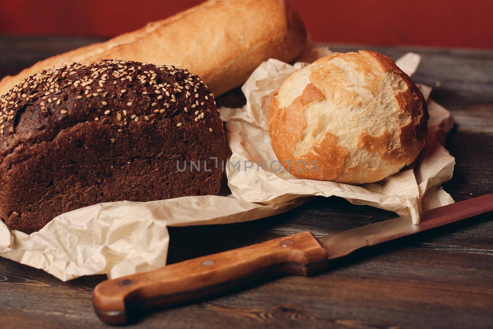 loaf of rye bread and flour products on paper packaging knife on a wooden table and red background. High quality photo