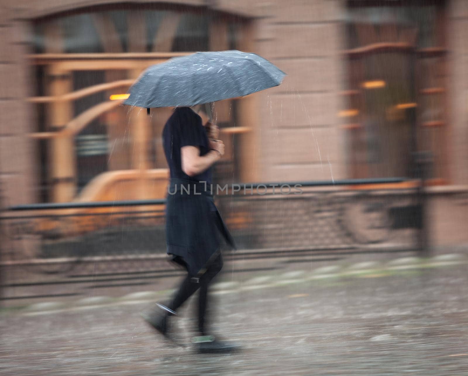 Shower. Woman walking down the street in rainy day. Intentional motion blur