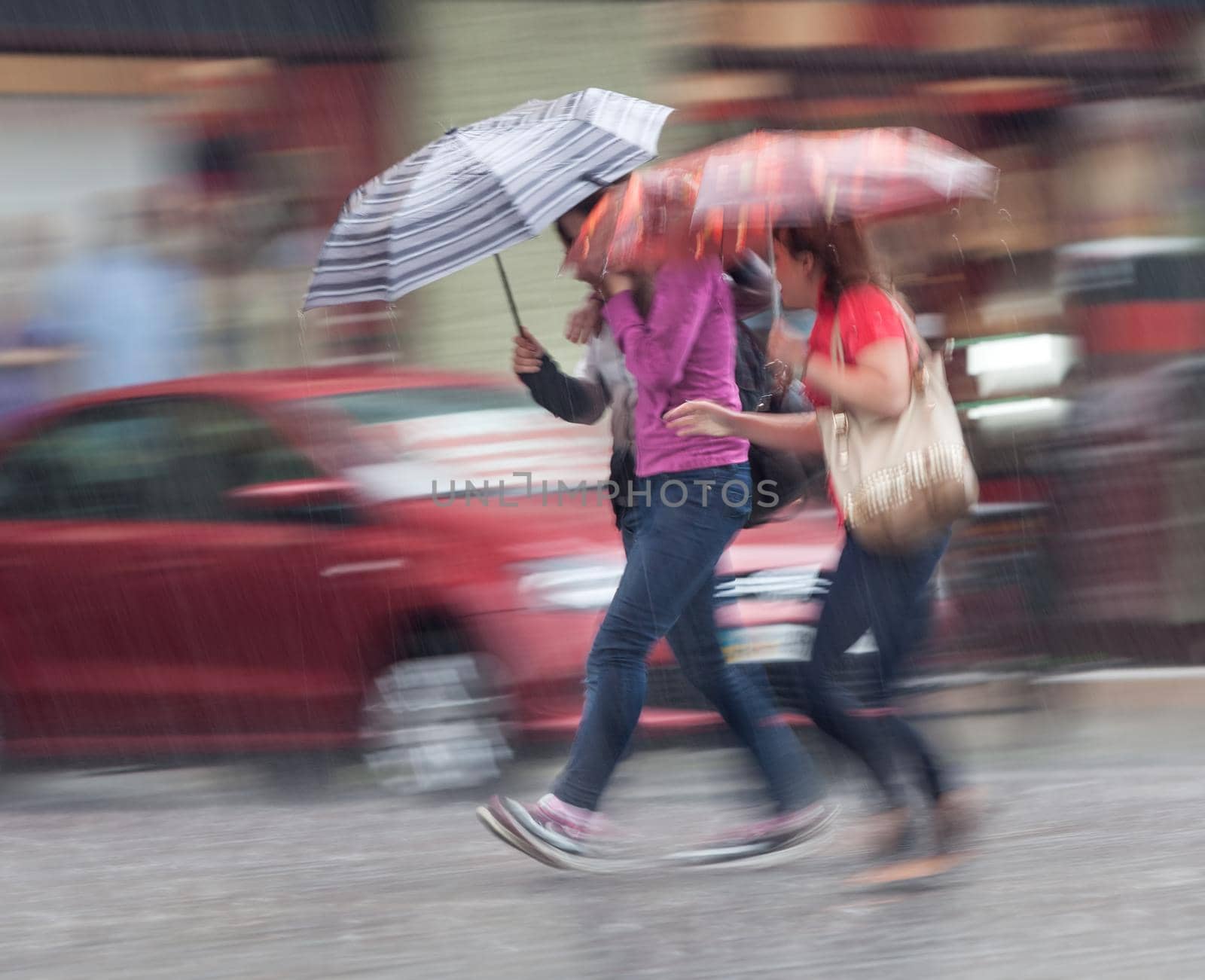 Group of young people walking down the street in rainy day. Intentional motion blur