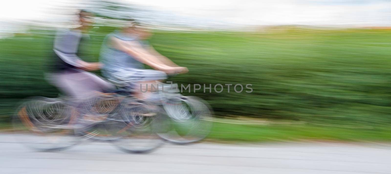 Two teenagers cyclists in traffic on the city roadway. Intentional motion blur