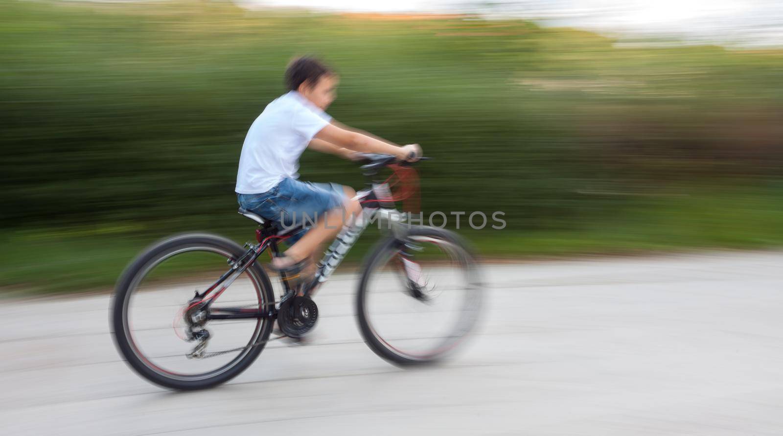 Boy cyclist in traffic on the city roadway. Intentional motion blur