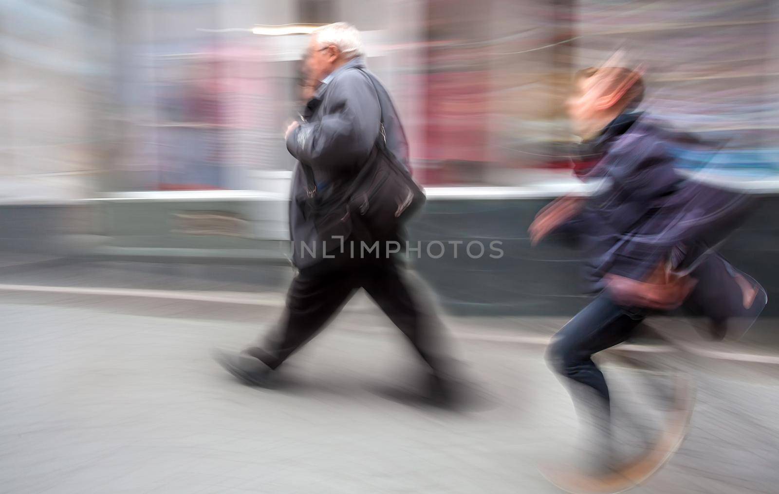 Running boy and an elderly man walking along the streets of the old town. Intentional motion blur