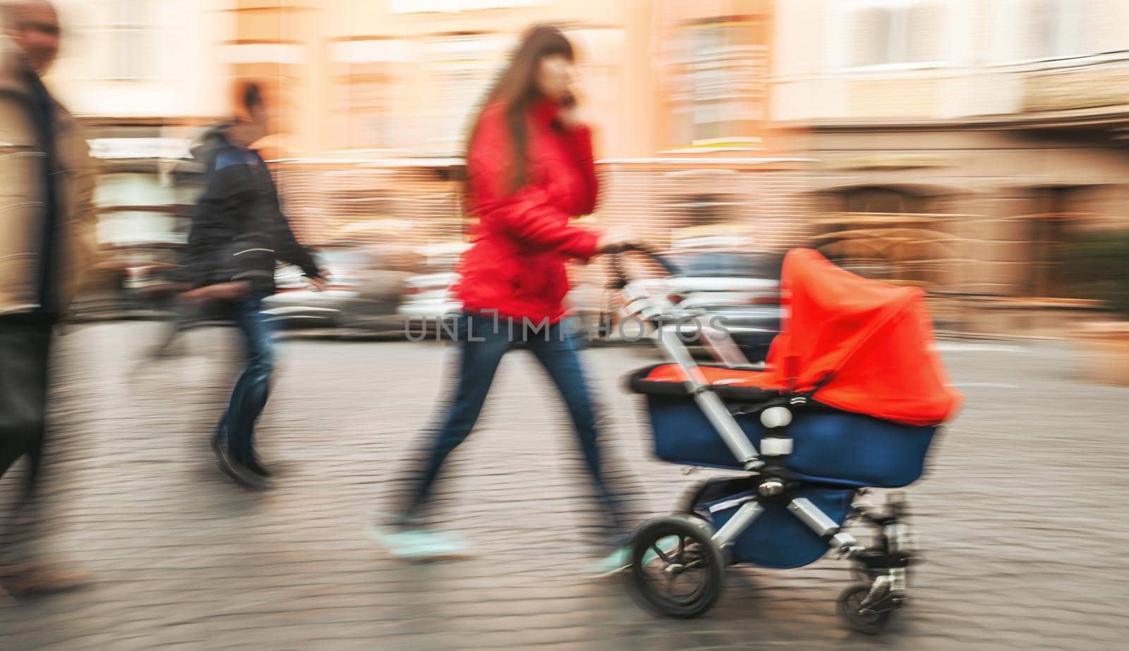 Mother with small children and a pram walking down the street. Intentional motion blur