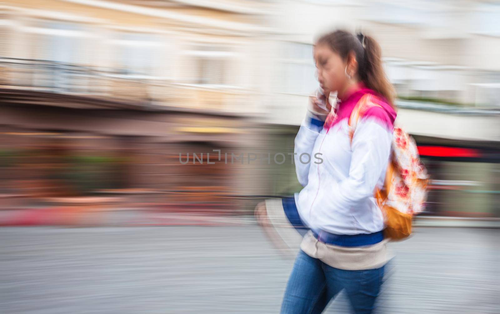 Abstract image of a young woman talking on a cell phone in a hurry. Intentional motion blur
